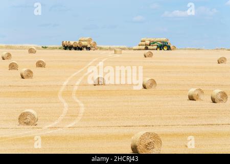 Zugmaschine und Anhänger mit Heuballen in ländlichen Landschaft Stockfoto