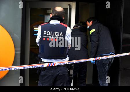 Vendrell, Spanien. 31st Dez 2021. Ein Agent der katalanischen Polizei wacht über den Eingang des Büros der CaixaBank, während zwei Agenten am Ort des Diebstahls Proben sammeln.Ein Mann mit einem Messer führt einen Raub in einem Büro der Bank CaixaBank in El Vendrell (Tarragona, Spanien) durch. Flucht mit einer Sammlung, die noch von den Bankverantwortlichen bestimmt werden muss. Die katalanische Polizei untersucht den Ort des Diebstahls und sucht nach Fingerabdrücken des Räubers (Foto: Ramon Costa/SOPA Images/Sipa USA) Quelle: SIPA USA/Alamy Live News Stockfoto