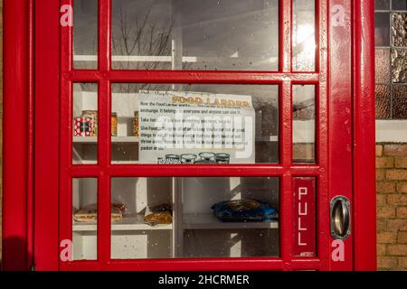 Speisekammer in einem alten roten Telefonkasten vor einer Kirche, Aldershot, Hampshire, Großbritannien Stockfoto