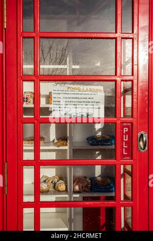 Speisekammer in einem alten roten Telefonkasten vor einer Kirche, Aldershot, Hampshire, Großbritannien Stockfoto