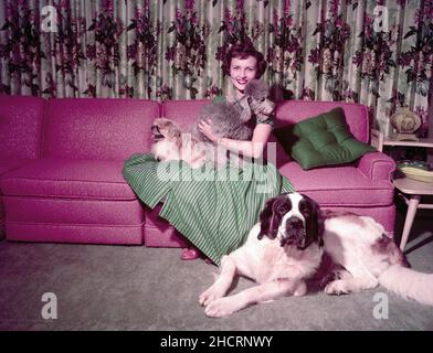 Um 1957, Hollywood, Kalifornien, USA: Die amerikanische Schauspielerin und Komikerin BETTY WHITE sitzt auf einer karmesinroten Couch in grün-schwarzem Strippkleid, umgeben von ihren Hunden. (Bild: © Globe Photos/ZUMA Press Wire) Stockfoto