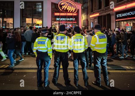 London, Großbritannien. 31st. Dezember 2021. Silvester: Die Polizei beobachtet und beobachtet die Menschenmassen im Piccadilly Circus. Kredit: Guy Corbishley/Alamy Live Nachrichten Stockfoto