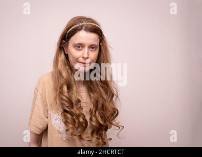 Junge Frau mit gewelltem goldgelbfarbenen langen Haaren und goldenem Haarreif Stockfoto