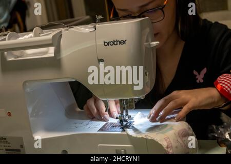 Chinesische Frau, die eine neue computergesteuerte Nähmaschine benutzt, Hongkong, China. Stockfoto