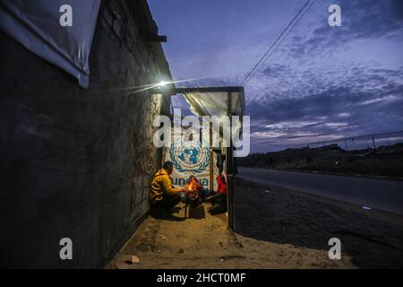 Gaza, Palästina. 31st Dez 2021. Eine palästinensische Familie sitzt am Feuer, um sich vor ihrem Haus bei kaltem Wetter am Rande des Flüchtlingslagers Khan Yunis aufzuwärmen. (Foto von Yousef Masoud/SOPA Images/Sipa USA) Quelle: SIPA USA/Alamy Live News Stockfoto