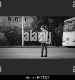 30th. August 2020, Russland, Tosmk, Frau wartet auf Bus auf der Straße schwarz und weiß Stockfoto