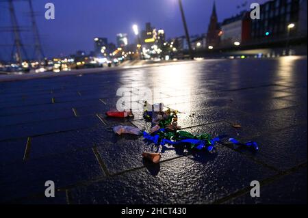 Hamburg, Deutschland. 01st Januar 2022. Konfetti-Schlangen und verbranntes Feuerwerk liegen auf dem nassen Boden in der Nähe der Landungsbrücken. Der Silvesterabend in Hamburg war aufgrund von Corona viel ruhiger als sonst. Tausende waren jedoch im Stadtzentrum unterwegs - trotz des Versammlungsverbots. Die Polizei erließ mehrere Vertreibungen. Quelle: Jonas Walzberg/dpa/Alamy Live News Stockfoto