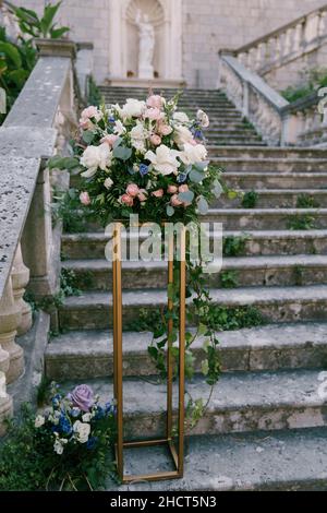 Blumenstrauß steht auf einem hohen Metallständer auf steinernen Stufen an der Balustrade Stockfoto