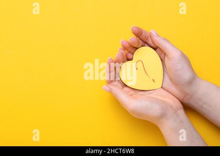 Frau mit herzförmiger Haftnotiz und Fragezeichen auf gelbem Hintergrund Stockfoto