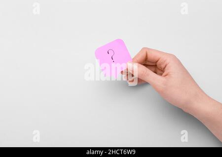Frau mit Haftnotiz und Fragezeichen auf hellem Hintergrund Stockfoto