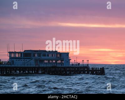 Worthing Beach, Worthing, Großbritannien. 1st Januar 2022. Die Menschen stehen am Ende des Worthing Pier und beobachten, wie die Sonne am ersten Tag des 2022. September über dem Worthing Pier aufgeht. Bild nach Kredit: Julie Edwards/Alamy Live News Stockfoto