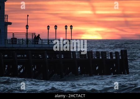 Worthing Beach, Worthing, Großbritannien. 1st Januar 2022. Die Menschen stehen am Ende des Worthing Pier und beobachten, wie die Sonne am ersten Tag des 2022. September über dem Worthing Pier aufgeht. Bild nach Kredit: Julie Edwards/Alamy Live News Stockfoto