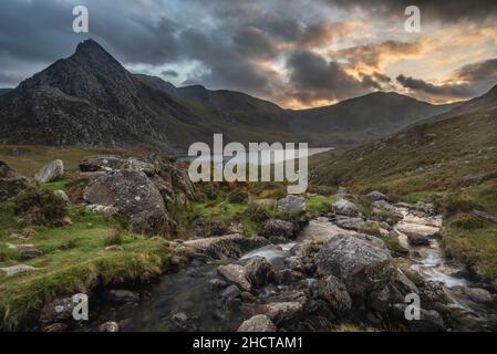 Episch dramatische Landschaftsaufnahme von Llyn Ogwen und Tryfan im Snowdonia National Park mit Bach und Felsen im Vordergrund Stockfoto