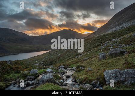 Episch dramatische Landschaftsaufnahme von Llyn Ogwen und Tryfan im Snowdonia National Park mit Bach und Felsen im Vordergrund Stockfoto