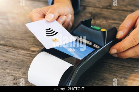 Kontaktloses Zahlungskonzept, weibliche Kundin hält Kreditkarte in der Nähe der nfc-Technologie am Schalter, Kunde macht Transaktionsrechnung auf Terminal rfid cas Stockfoto