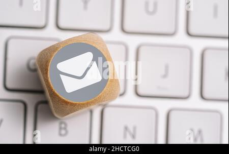 E-Mail-Symbol auf einem Holzwürfel auf einer Tastatur. Kontakt- und Kommunikationsmethoden Konzeptbild Stockfoto