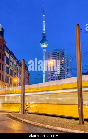 Der berühmte Fernsehturm in Berlin bei Nacht mit einer fahrenden Straßenbahn Stockfoto