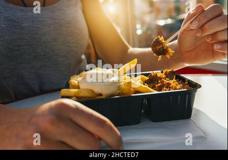 Deutsche Currywurst-Wurst mit Curryketchup, gerösteten Zwiebeln und Pommes Frites mit Mayonnaise in der Stadt Stockfoto