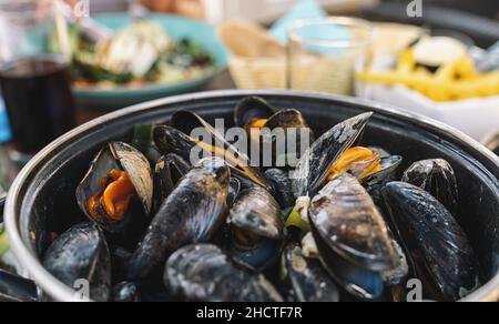 Muscheln in einer Schüssel mit Pommes Frites in einem Restaurant. Ein klassisches Gericht in Belgien, Frankreich und den Niederlanden. Stockfoto