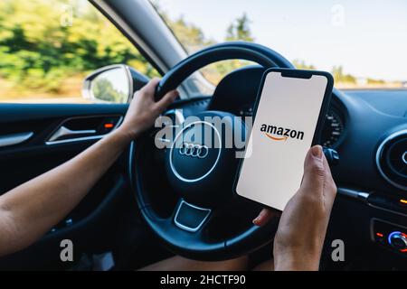 Frau Hand hält iphone XS Amazon Logo auf dem Bildschirm in einem Auto. Amazon.com, Inc. Amerikanisches internationales E-Commerce-Unternehmen. Stockfoto