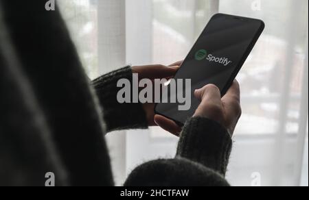Frau, die ein iPhone XS hält, um die spotify-App auf einem Fenster zu öffnen, ist Spotify ein Musikdienst, der legales Streaming von Musik anbietet. Stockfoto