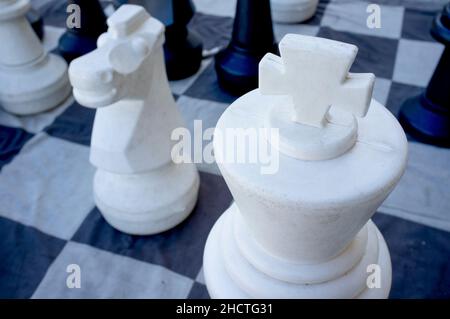 Schach auf der Straße mit übergroßen Stücken auf Leinenteppich. Selektiver Fokus auf King Piece Stockfoto