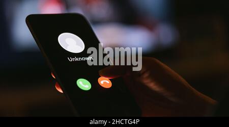 Unbekannte Nummer, die mitten in der Nacht anruft. Anruf von einem Fremden. Person mit Handy und Smartphone im Wohnzimmer spät. Unerwarteter Anruf Stockfoto