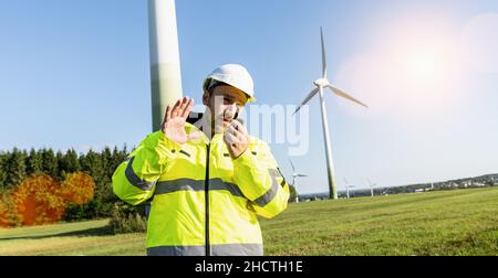 Ingenieur, der an Windenergieanlagen arbeitet und über das Walkie-Talkie spricht, um die Arbeit zu kontrollieren Stockfoto