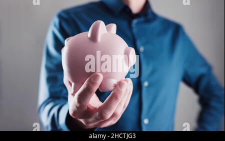 Männliche Hand mit einem Sparschwein Stockfoto
