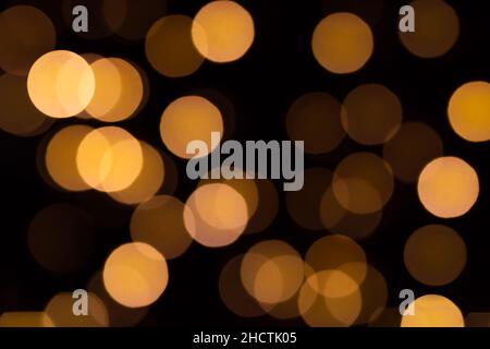 Weihnachten und Happy New Year Bokeh abstrakte Lichter in warmen Orange Tönen auf verschwommenem schwarzem Hintergrund Stockfoto