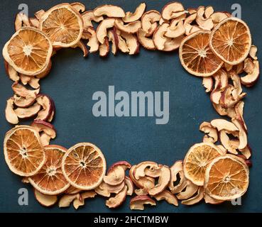 Rahmen aus getrockneten Apfel- und Orangenscheiben auf blauem Hintergrund mit Kopierraum Stockfoto