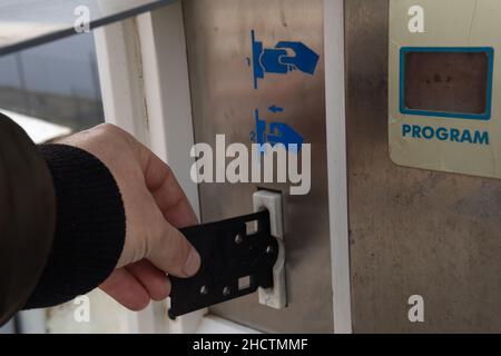 Nahaufnahme einer kaukasischen Hand, die eine schwarze Karte in eine Waschmaschine einführt Stockfoto