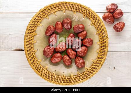 Mehrere süße getrocknete ziziphus-Beeren mit einer Keramikplatte auf einem Holztisch, Nahaufnahme, Draufsicht. Stockfoto