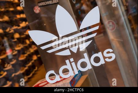 Adidas Logo auf einem Schaufenster. Adidas ist ein deutscher multinationaler Konzern, der Sportbekleidung und Accessoires entwirft und herstellt. Stockfoto