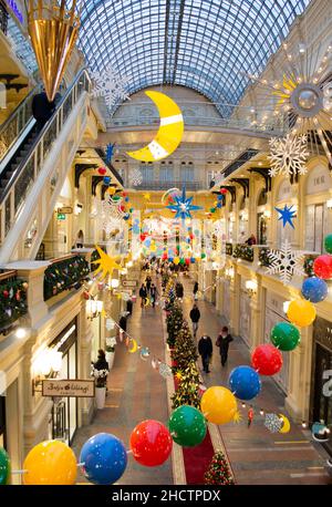Moskau, Russland, Dezember 2021: Helle, bunte Weihnachtsdekoration im Einkaufszentrum: Riesensterne, Perlen, Mond, Schneeflocken. Vertikales Bild. Stockfoto