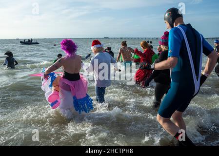 Jubilee Beach, Southend on Sea, Essex, Großbritannien. 1st Januar 2022. Die Menschen haben sich für wohltätige Zwecke in die kalten Gewässer der Themsemündung gebracht, um Gelder für die lokale Niederlassung der Royal National Lifeboat Institution zu sammeln. Mitglieder der RNLI waren aus Sicherheitsgründen zur Verfügung, viele der Schwimmer trugen Kostüme in schicken Kleidern. Rund 300 Personen nahmen daran Teil. Schwimmer, die ins Meer Rennen Stockfoto