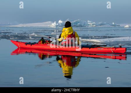 Norwegen, Spitzbergen. Kajakfahren im Meer zwischen Eisbergen in ruhiger See. Stockfoto