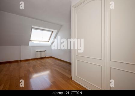 Leeres Zimmer mit Loft-Decken, Fenster und weißem Einbauschrank Stockfoto