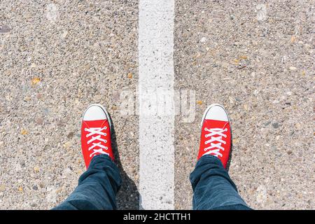 Mann, der auf einer grunge asphaltierten Stadtstraße mit weißer Linie auf dem Boden steht, aus der Perspektive Stockfoto