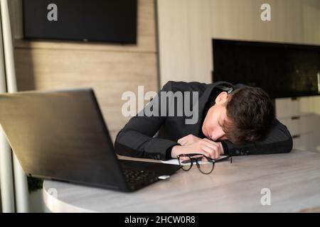 Schlafarbeiter am Arbeitsplatz, müder Mitarbeiter auf dem Tisch liegend, schlafender Geschäftsmann im Büro, Routinearbeit, chronischer Schlafmangel, Schlaflosigkeit Stockfoto