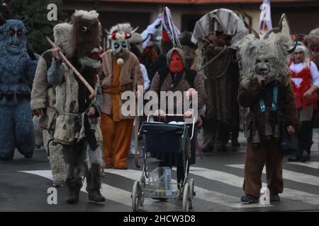 Mummers in traditionellen Kostümen tourten am ersten Tag des Jahres 2022 durch die Straßen von Godech. Menschen mit einer Maske namens Kukeri tanzen Stockfoto