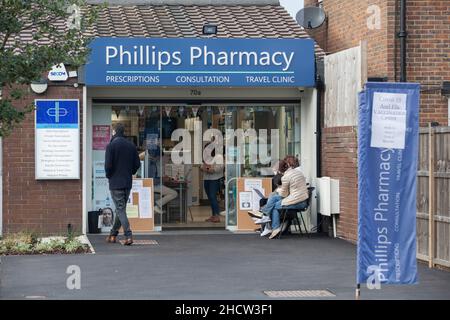 London, Großbritannien, 1. Januar 2022: Eine Apotheke in Clapham ist auch am Neujahrstag geöffnet, um den Einheimischen weiterhin Auffrischungsjabs oder erste oder zweite Impfungen anzubieten. Lambeth hat eine der höchsten Infektionsraten für die omicron-Variante des Coronavirus und auch eine der niedrigsten Impfraten im Land. Die Menschen sind bereit, sich bei mildem, trockenem Wetter draußen anzustellen. Anna Watson/Alamy Live News Stockfoto