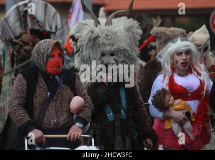 Mummers in traditionellen Kostümen tourten am ersten Tag des Jahres 2022 durch die Straßen von Godech. Menschen mit einer Maske namens Kukeri tanzen Stockfoto