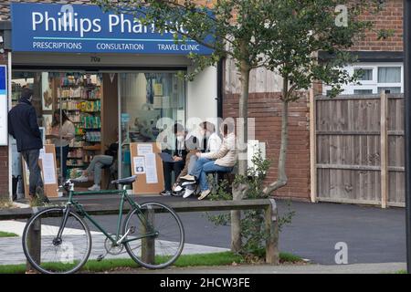 London, Großbritannien, 1. Januar 2022: Eine Apotheke in Clapham ist auch am Neujahrstag geöffnet, um den Einheimischen weiterhin Auffrischungsjabs oder erste oder zweite Impfungen anzubieten. Lambeth hat eine der höchsten Infektionsraten für die omicron-Variante des Coronavirus und auch eine der niedrigsten Impfraten im Land. Die Menschen sind bereit, sich bei mildem, trockenem Wetter draußen anzustellen. Anna Watson/Alamy Live News Stockfoto