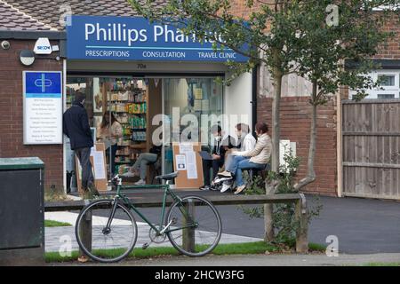 London, Großbritannien, 1. Januar 2022: Eine Apotheke in Clapham ist auch am Neujahrstag geöffnet, um den Einheimischen weiterhin Auffrischungsjabs oder erste oder zweite Impfungen anzubieten. Lambeth hat eine der höchsten Infektionsraten für die omicron-Variante des Coronavirus und auch eine der niedrigsten Impfraten im Land. Die Menschen sind bereit, sich bei mildem, trockenem Wetter draußen anzustellen. Anna Watson/Alamy Live News Stockfoto