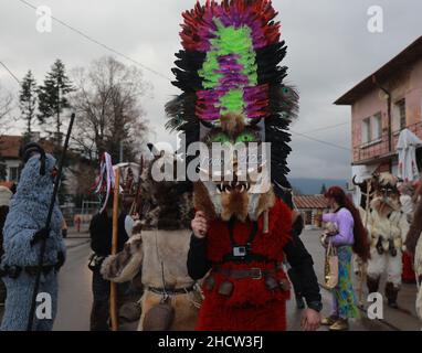 Mummers in traditionellen Kostümen tourten am ersten Tag des Jahres 2022 durch die Straßen von Godech. Menschen mit einer Maske namens Kukeri tanzen Stockfoto