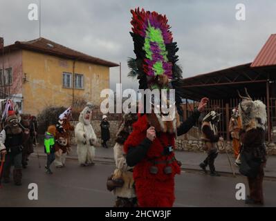 Mummers in traditionellen Kostümen tourten am ersten Tag des Jahres 2022 durch die Straßen von Godech. Menschen mit einer Maske namens Kukeri tanzen Stockfoto