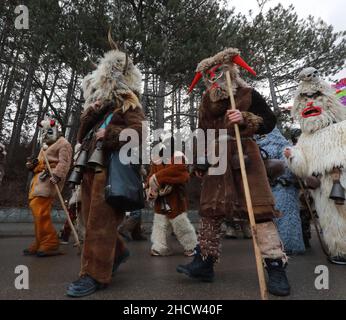 Mummers in traditionellen Kostümen tourten am ersten Tag des Jahres 2022 durch die Straßen von Godech. Menschen mit einer Maske namens Kukeri tanzen Stockfoto