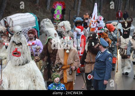 Mummers in traditionellen Kostümen tourten am ersten Tag des Jahres 2022 durch die Straßen von Godech. Menschen mit einer Maske namens Kukeri tanzen Stockfoto