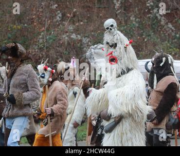 Mummers in traditionellen Kostümen tourten am ersten Tag des Jahres 2022 durch die Straßen von Godech. Menschen mit einer Maske namens Kukeri tanzen Stockfoto